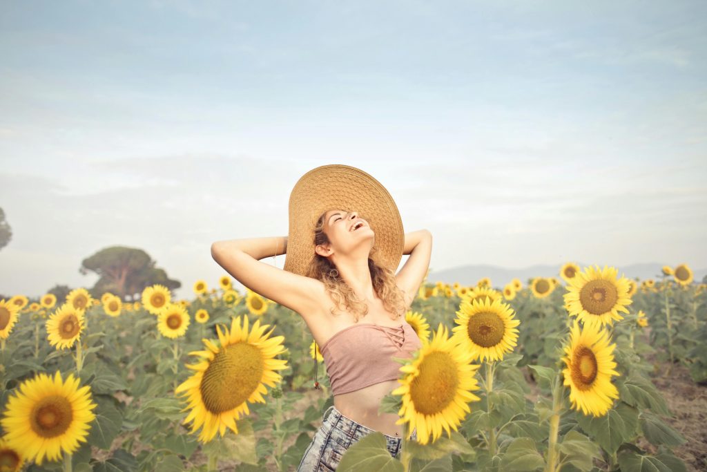 Happy woman soaking sun among sunflowers