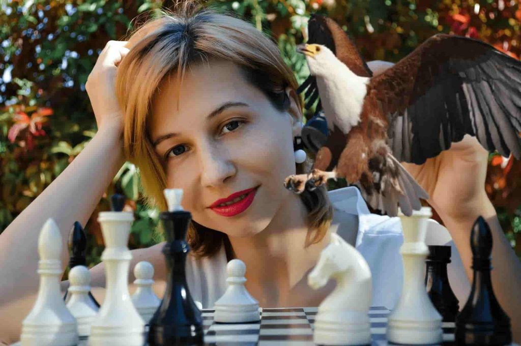 Woman playing chess with an eagle punching on the pieces