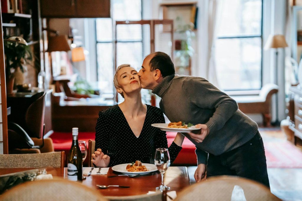 Husband loving kissing his wife over a meal.