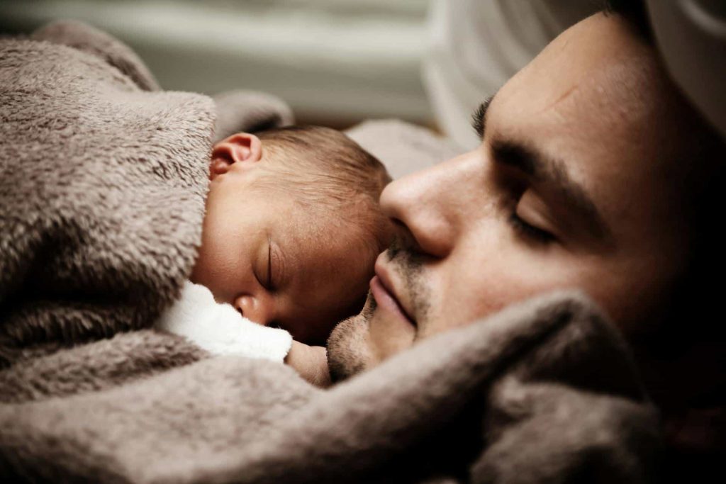 Man with sleeping baby resting on his chest, symbolizing Sabbath rest meaning.